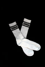 Pair of white Omnia Crew Socks crossed on black