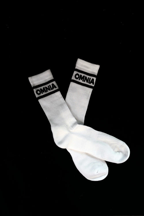 Pair of white Omnia Crew Socks crossed on black